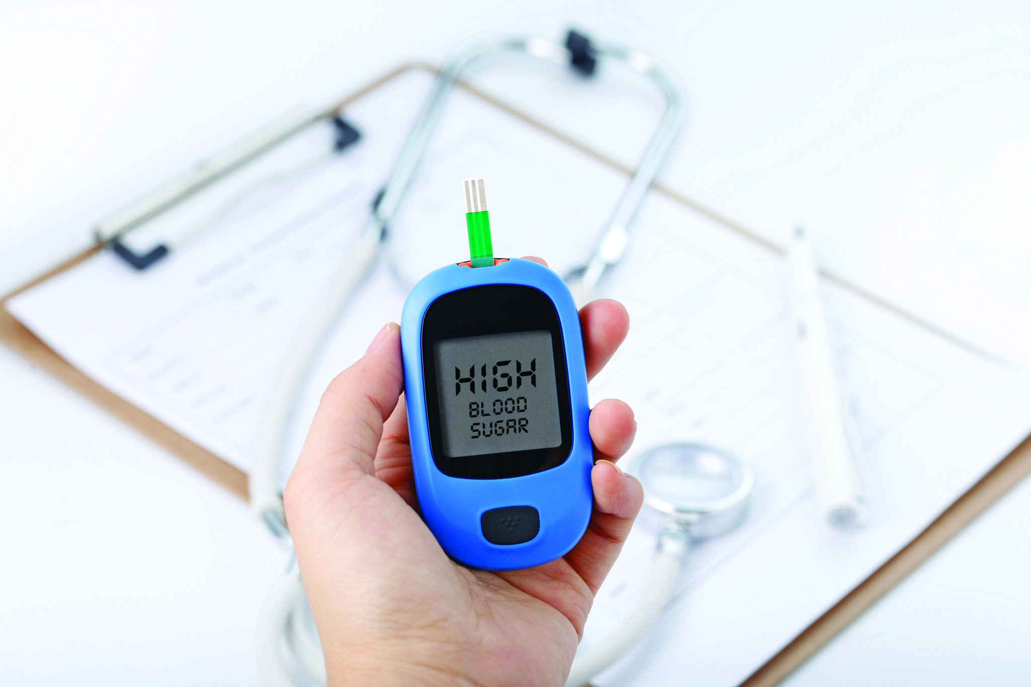 Hand holding a blood glucose meter measuring blood sugar.